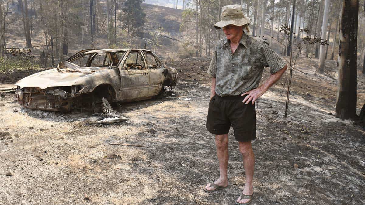 An elderly person inspects the damage next to his house after the bushfires