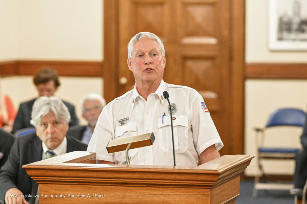 Gray haired man in fire chief uniform at a podium.